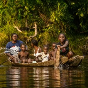 Mensen varen in traditionele houten boot op een Surinaamse rivier