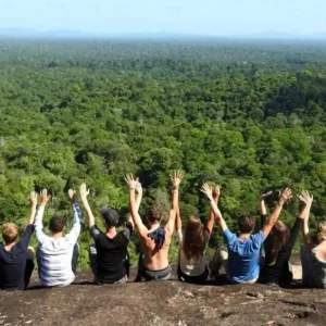 Groep reizigers met armen omhoog op een grote rots