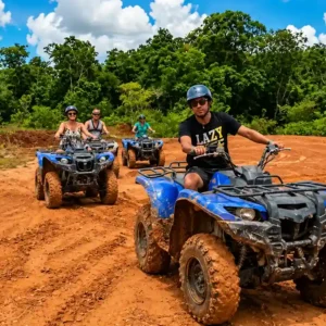 Een groep toeristen met helmen op rijdt op blauwe quads over een modderige, rode bauxietweg in Suriname.