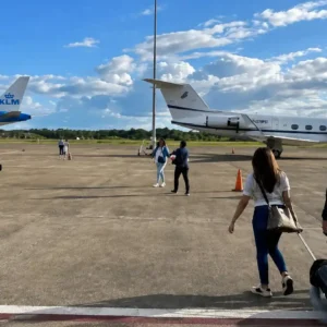 Passagiers lopen over het platform naar een privévliegtuig en een KLM-toestel op de internationale luchthaven van Suriname.